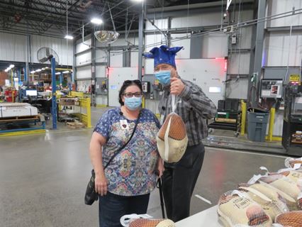 Two Raymond employees pose together while holding a frozen turkey.